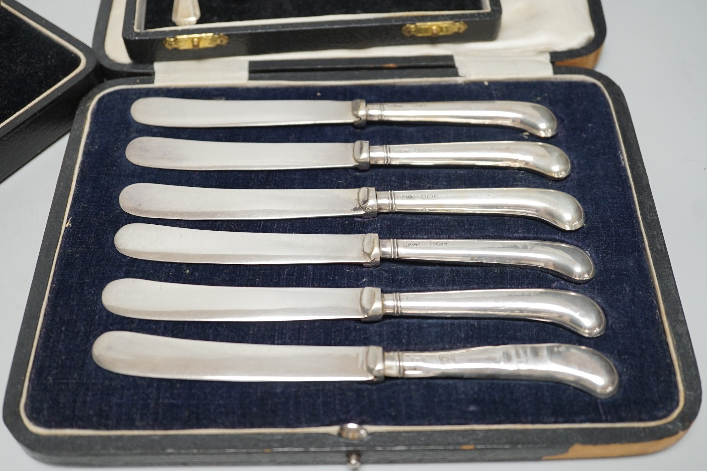 A cased George V three piece silver condiment set, Birmingham, 1928 and two other cased sets of flatware.
